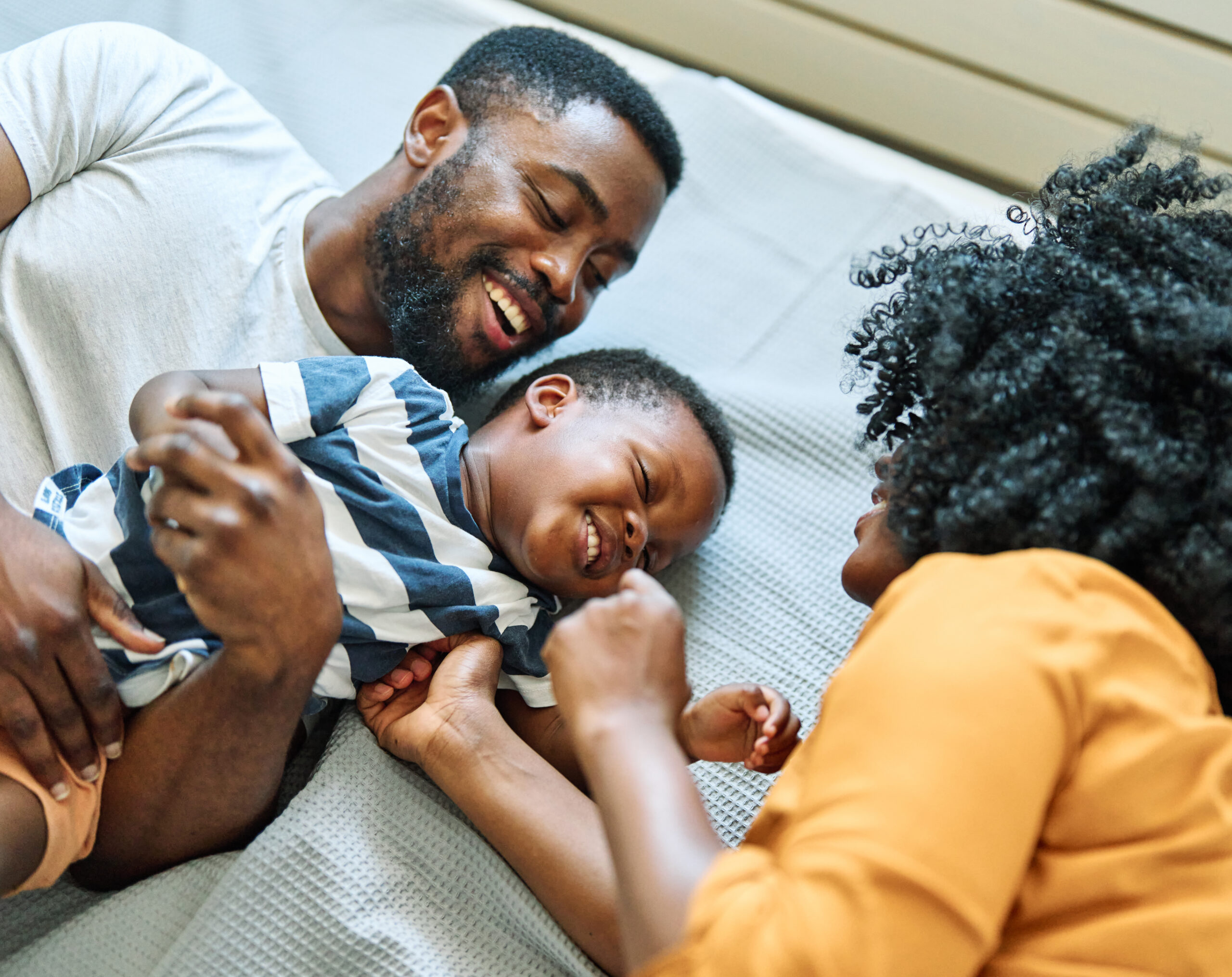 Portrait of mother, father and son having fun at home in bedroom, family life, parenting, love and bonding concepts