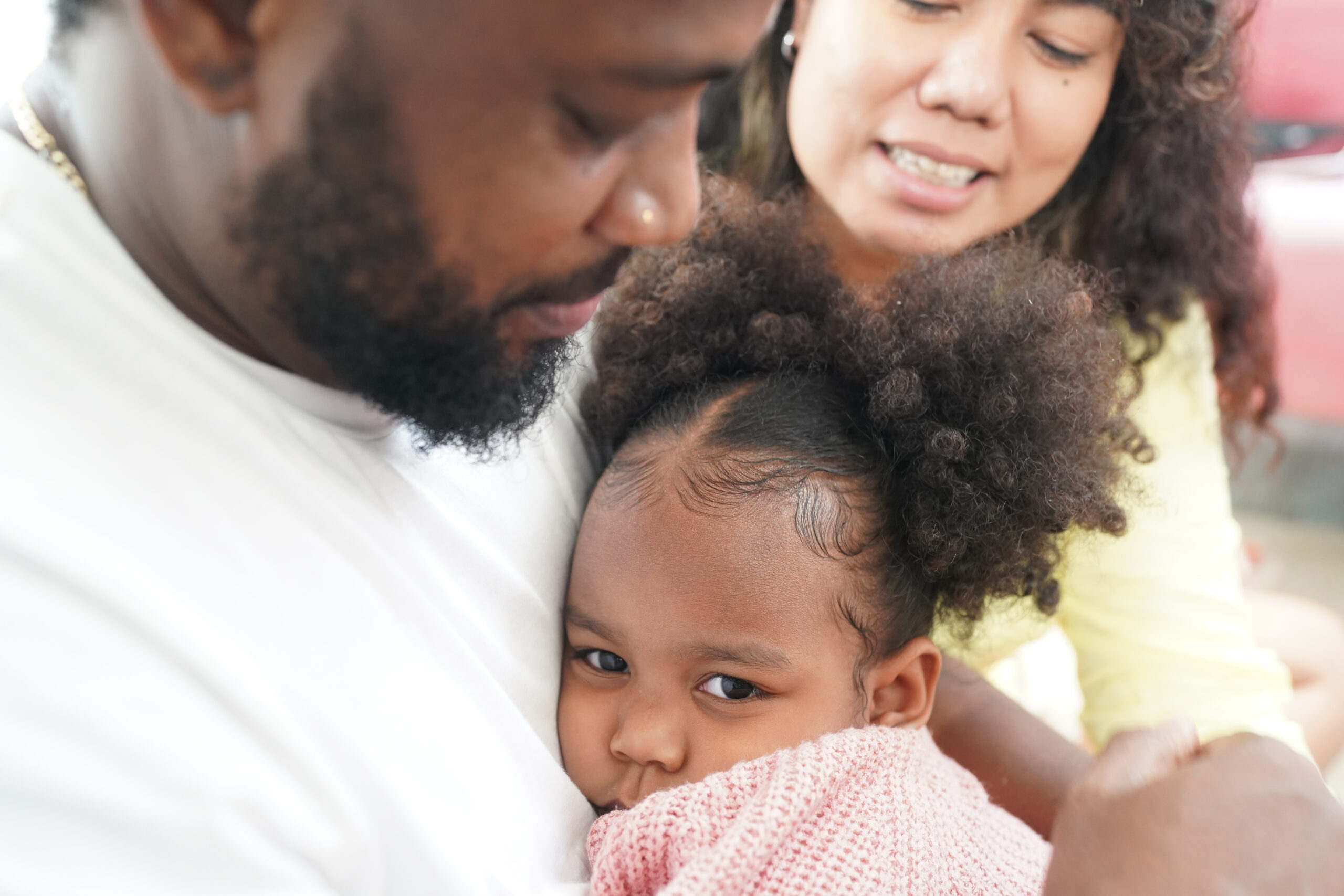 Shot of happy interracial family of mother father and their daughter inside modern apartment.