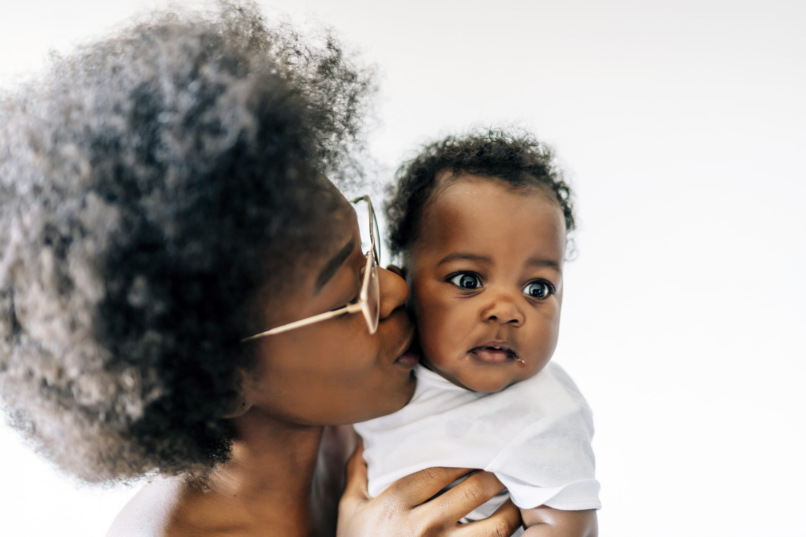 An African-American mother taking care and loving her baby against a white background