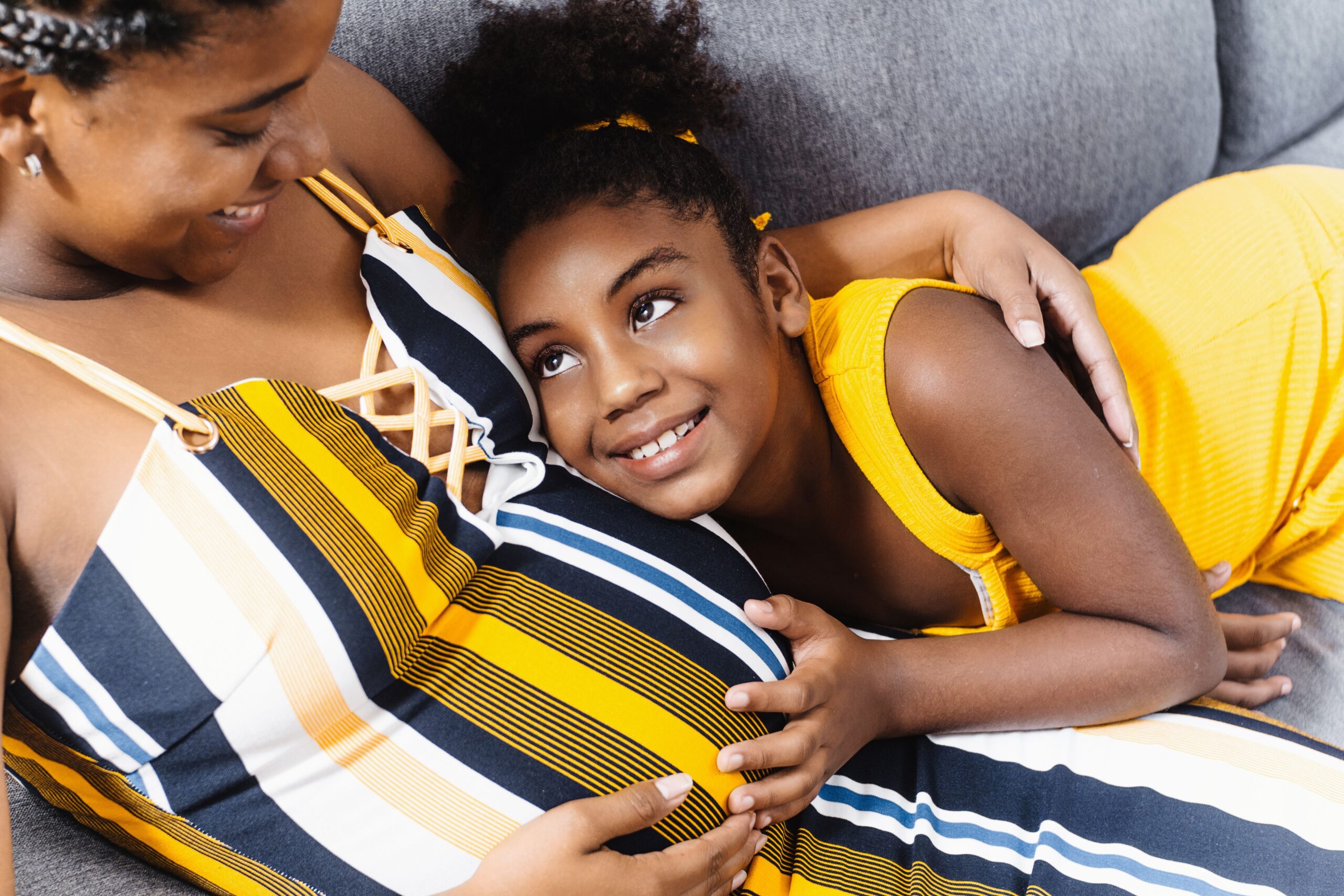 Little Black Girl and Her Pregnant Mom Embracing at Home. Family concept.