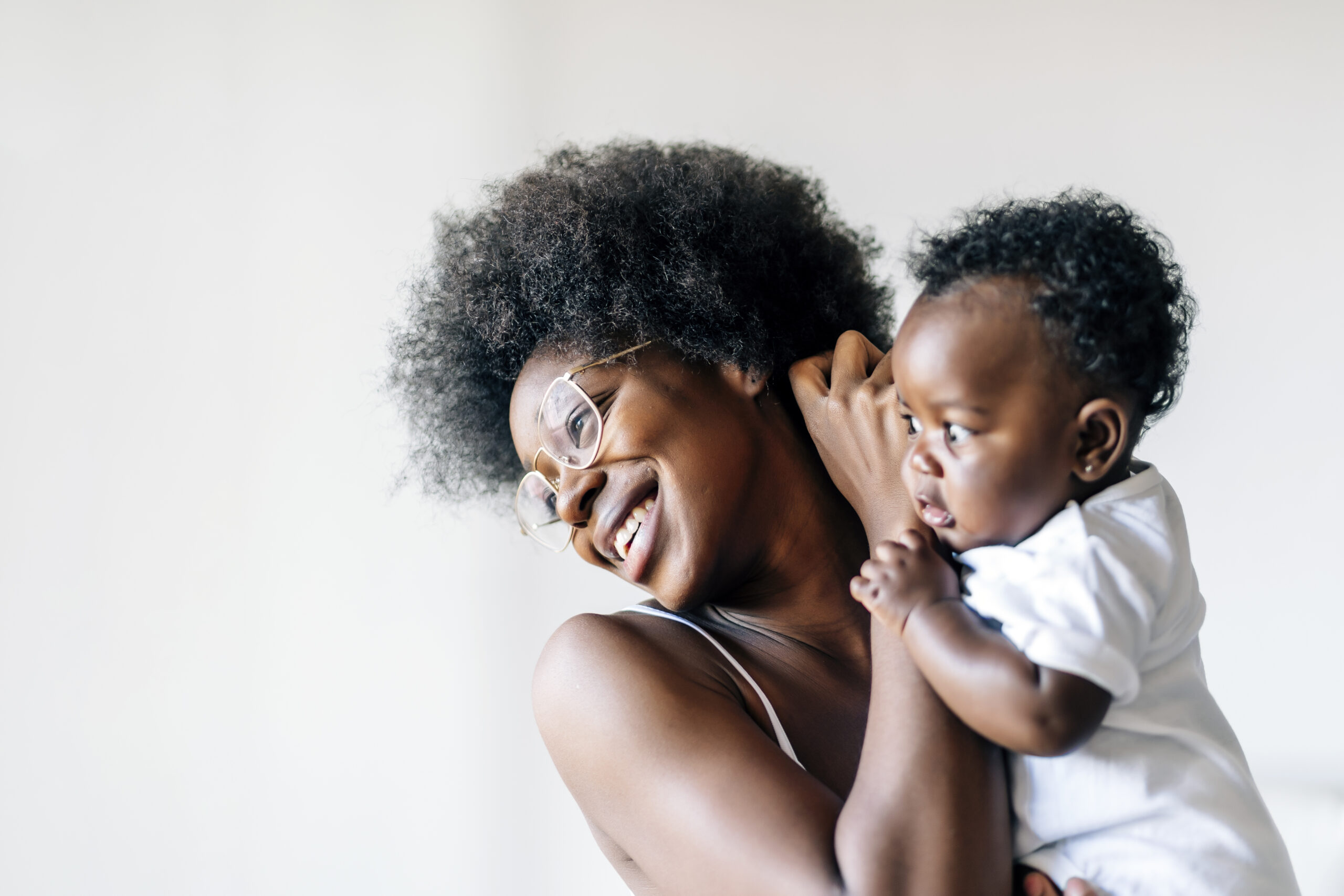 An African-American mother taking care and loving her baby against a white background