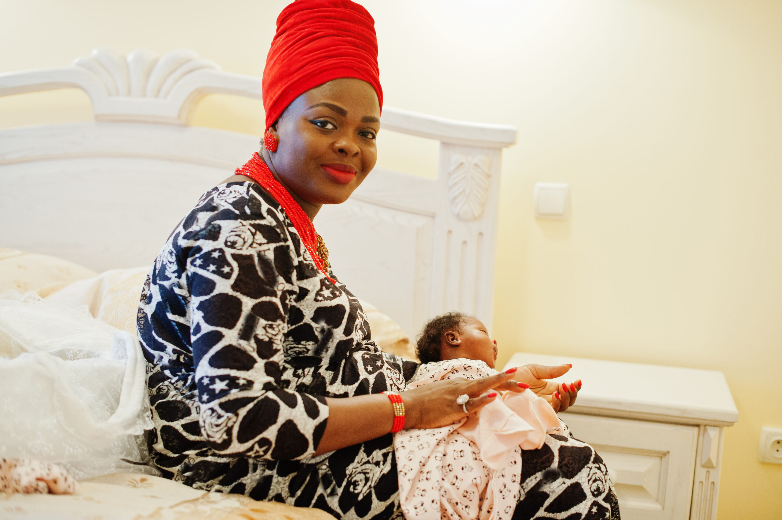 Beautiful black woman in ethnic clothing holding little baby.