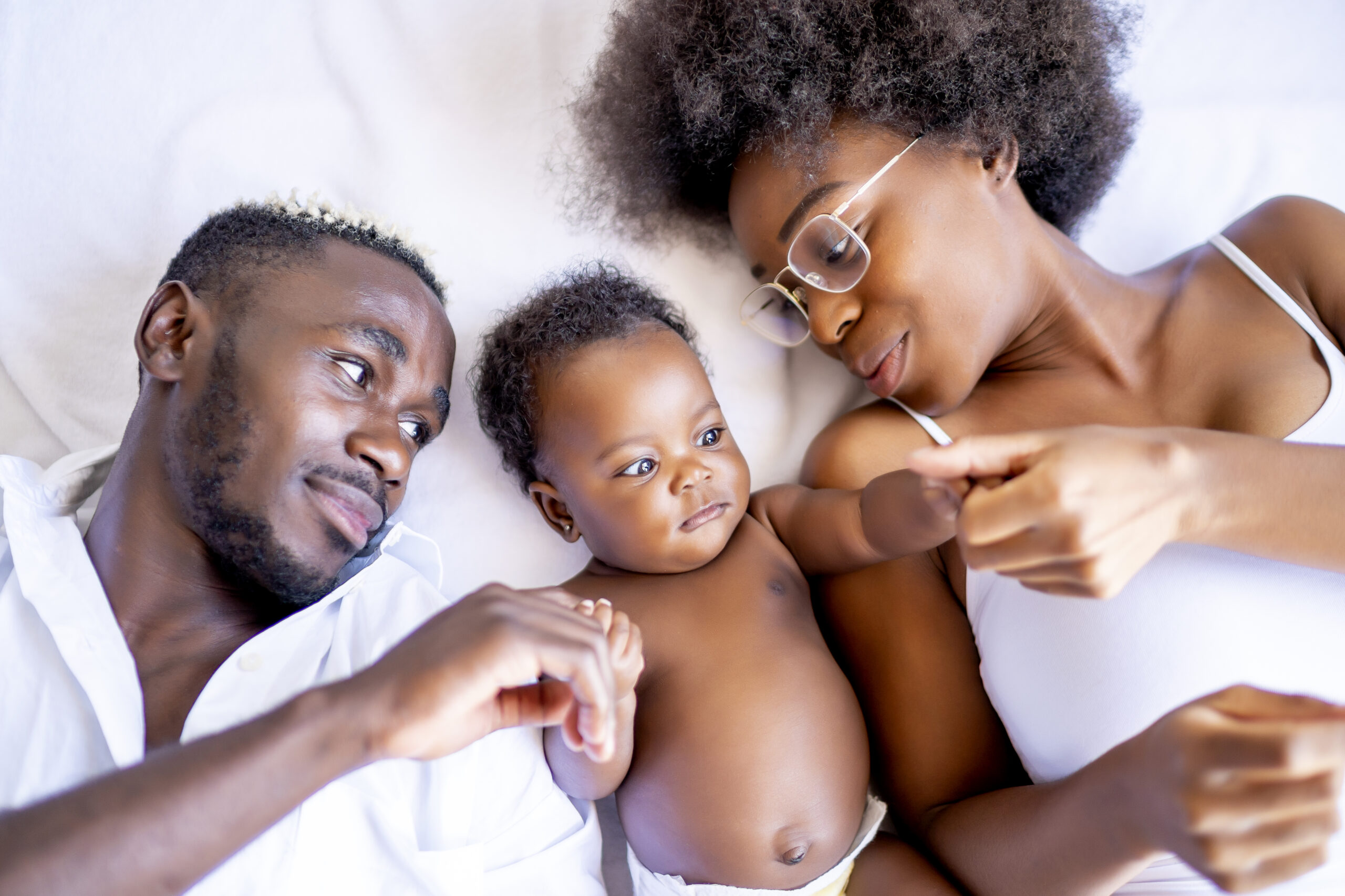 Happy family playing their baby in bed